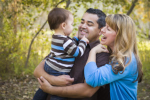 Happy Mixed Race Ethnic Family Having Fun Playing In The Park.