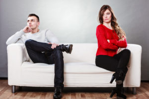 Young couple after quarrel sitting on sofa